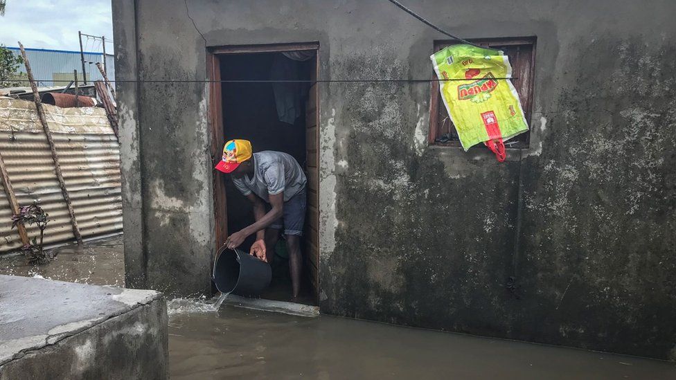A man using a bucket to clear water from his house
