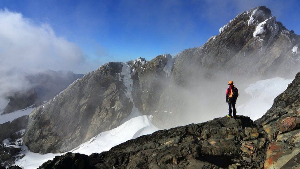 A hiker looking over to the summit of Margherita Peak, Rwenzori.