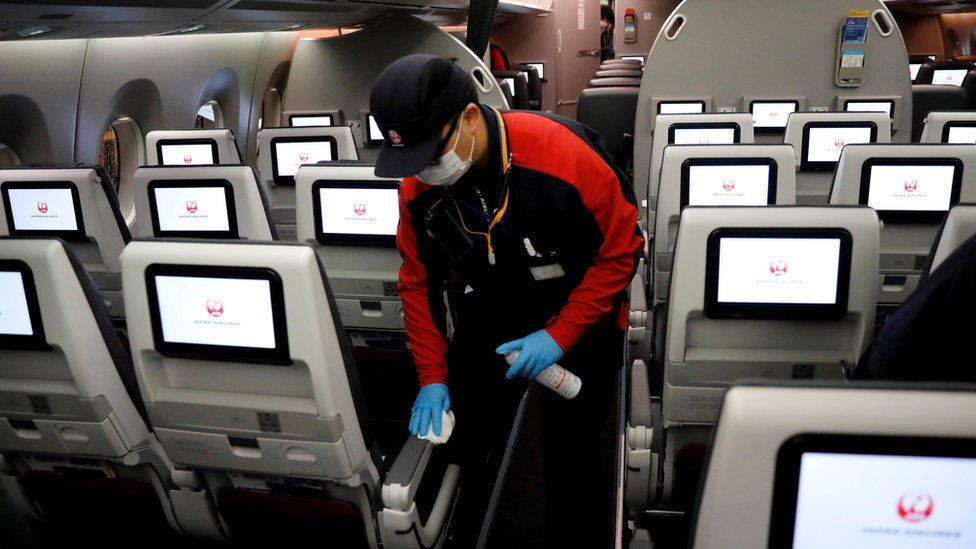 A staff member of Japan Airlines wearing a protective face mask and gloves cleans the cabin of a plane after performing a domestic flight