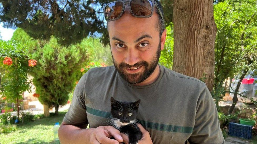 Reuters visuals journalist Issam Abdallah holds a kitten while posing for a picture in Saaideh, Lebanon
