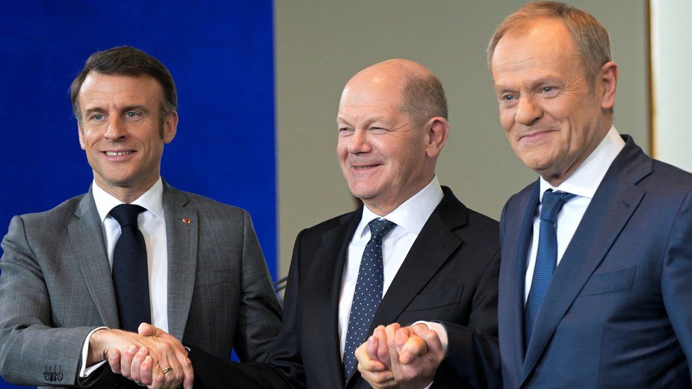 Emmanuel Macron, Olaf Scholz and Donald Tusk shaking hands.