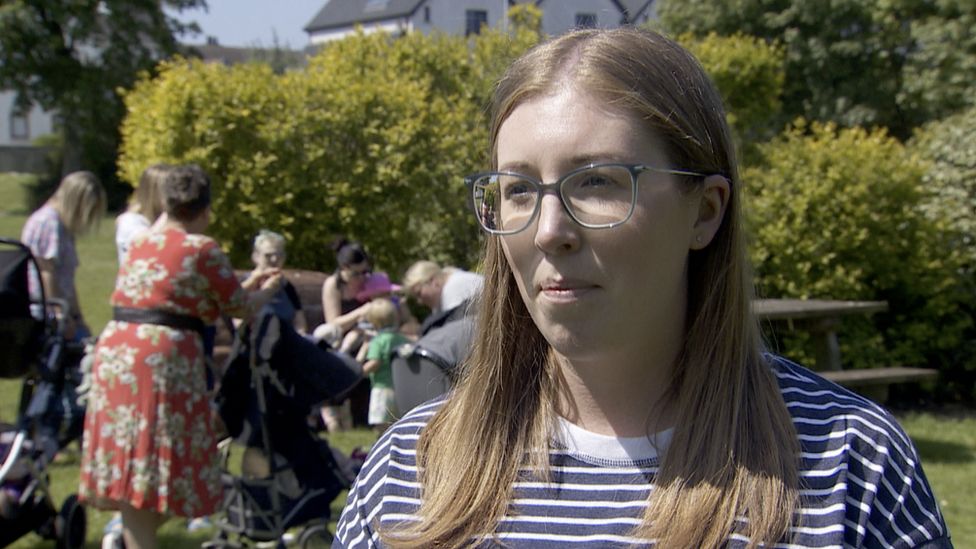 Laura Magee, a mother from Portrush, stands in a park wearing a blue and white striped top