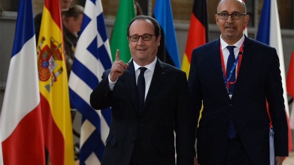 France's President Francois Hollande (centre) and French Junior Minister for European Affairs Harlem Desir in front of flags at summit in Brussels, on April 29, 2017