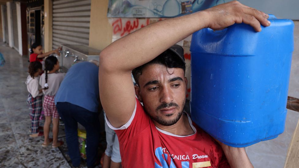 A man man collects water from a public water collection point in Gaza City