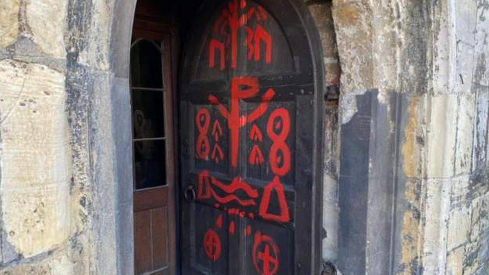 Wooden front door of the 13th-century St Olave's church in Marygate painted with red symbols