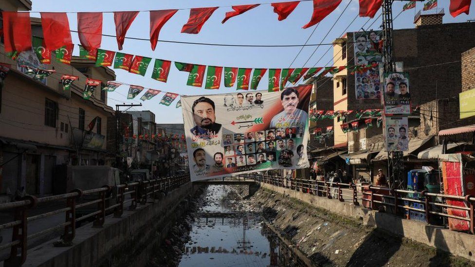 View of campaign posters and flags of political parties along a street, ahead of general elections, in Peshawar