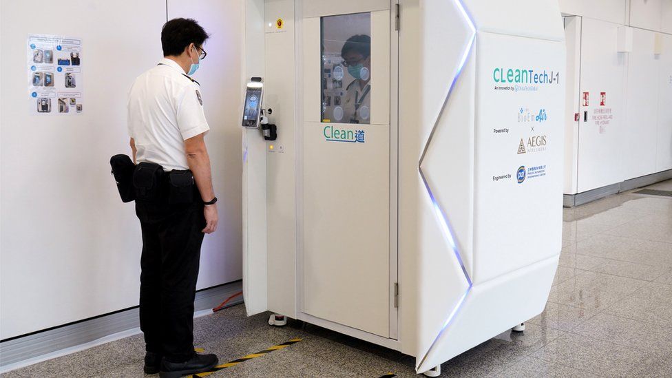 A member of staff goes through the CLeanTech full-body disinfection channel facility at Hong Kong International Airport, 24 April 2020