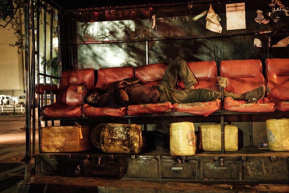 A man sleeps on shoe shine chairs in the late evening in Nairobi on 21 October 2021 after Kenya's president ordered the immediate lifting of the curfew that had been in place since March 2020