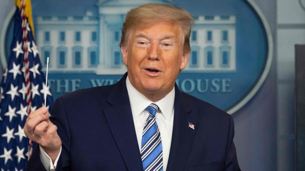 Donald Trump holds up a medical swab at a White House press briefing, 19 April 2020