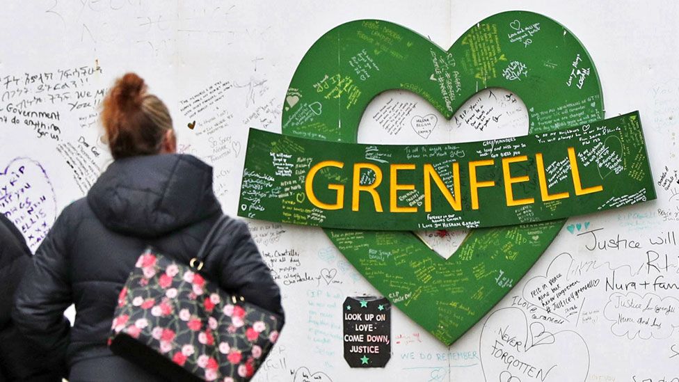 A woman walks towards the Grenfell Memorial Wall in the grounds of Kensington Aldridge Academy in February 2021