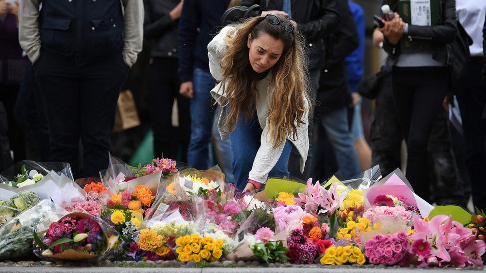 A woman lays flowers at a pedestrian crossing on the south side of London Bridge, close to Borough Market in London.