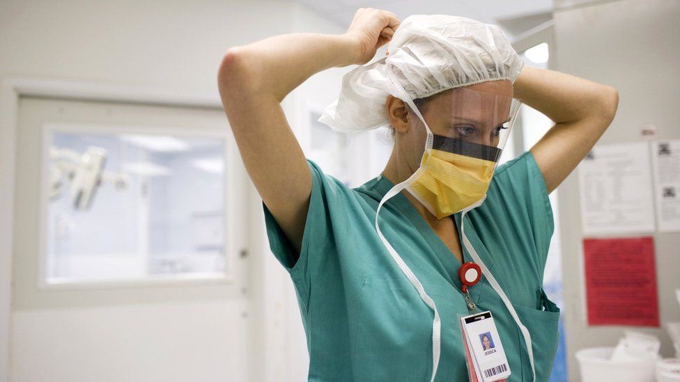 Stock image of a nurse putting on a face covering