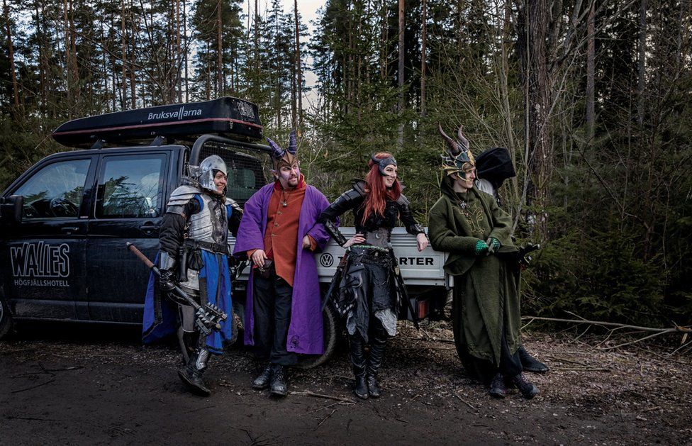 A group of live action role players lean against a van.