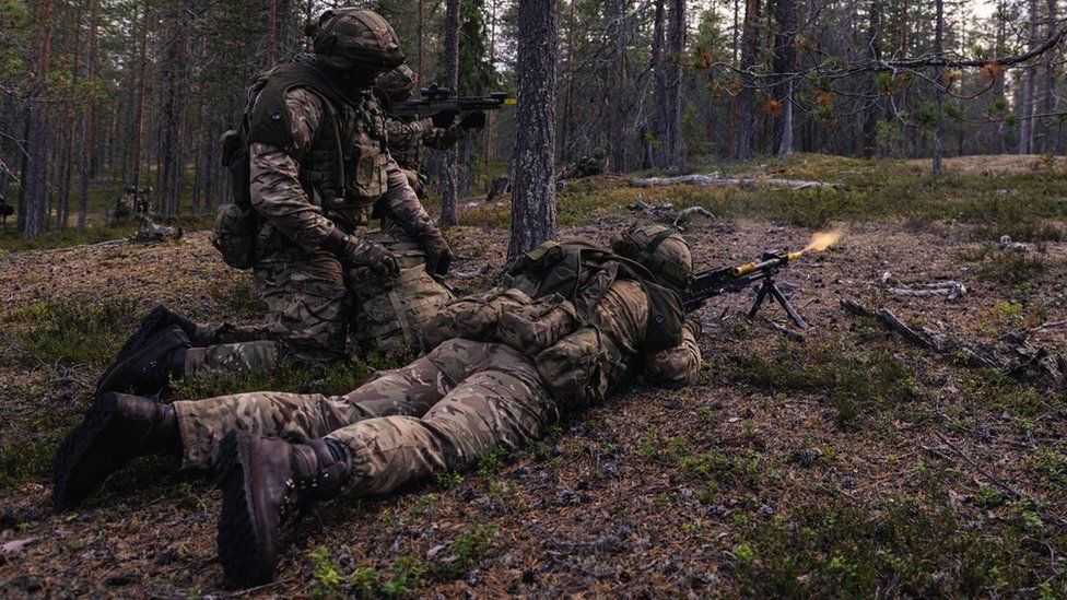 British troops are seen practising firing weapons in a forest while wearing army uniforms