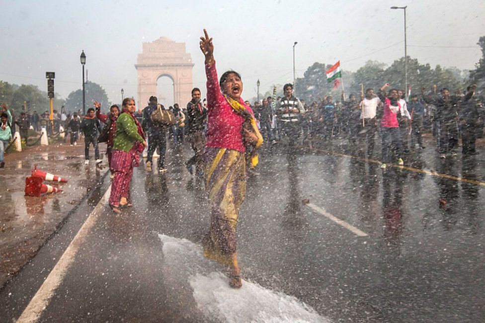 A protester chants slogans as she braces herself against the spray fired from police water canons during a protest against the Indian government's reaction to recent rape incidents in India, in front of India Gate on December 23, 2012 in New Delhi, India.