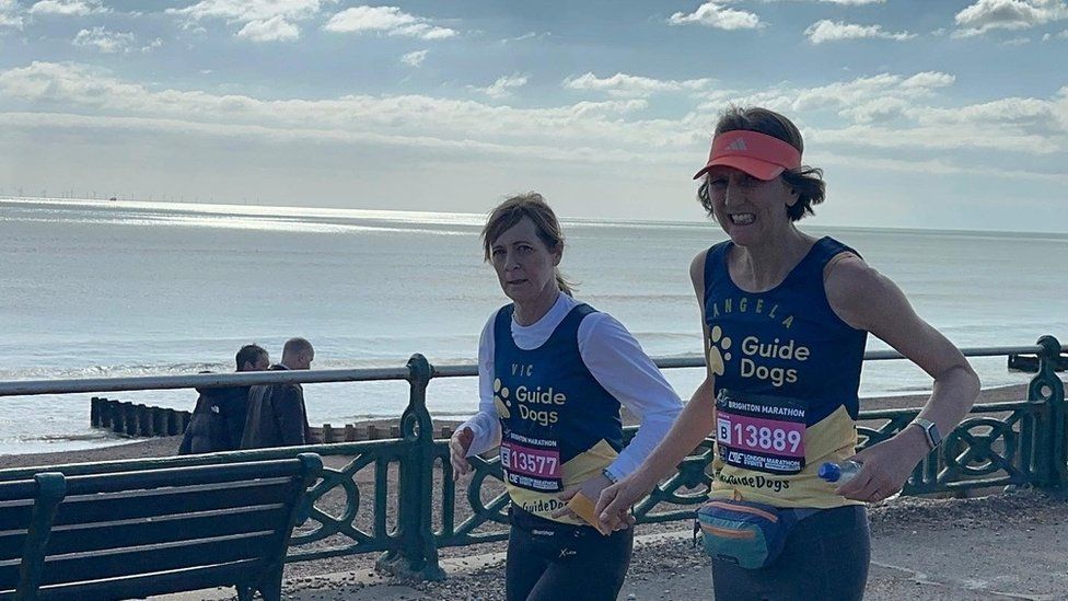 Angela Blackwell wearing a pink visor running next to Vicky Graimes along the seafront