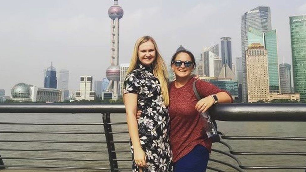 Two women pose for the camera in front of Shanghai's Oriental Pearl Tower