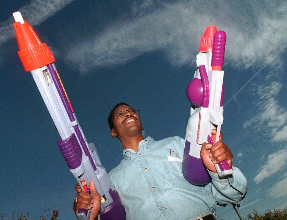 Lonnie Johnson holding some large super soaker guns