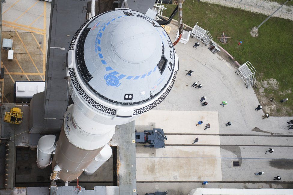 Starliner сидит на Atlas V, когда они выкатываются на стартовую площадку перед испытательным полетом в 2019 году