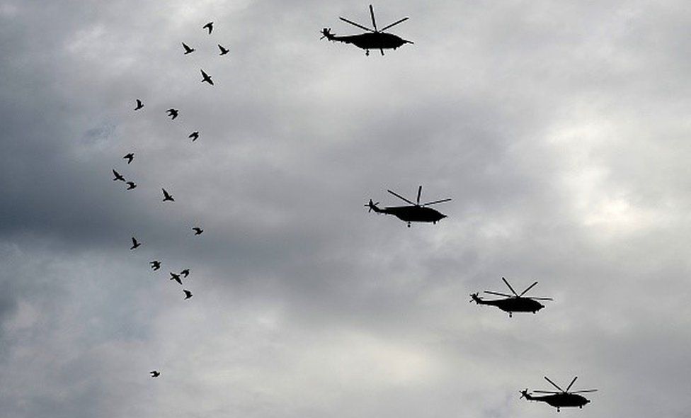 Chinese military helicopters, taking part in a rehearsal ahead of a military parade to mark the 70th anniversary of the end of World War II, fly over a flock of birds, in Beijing on August 23, 2015