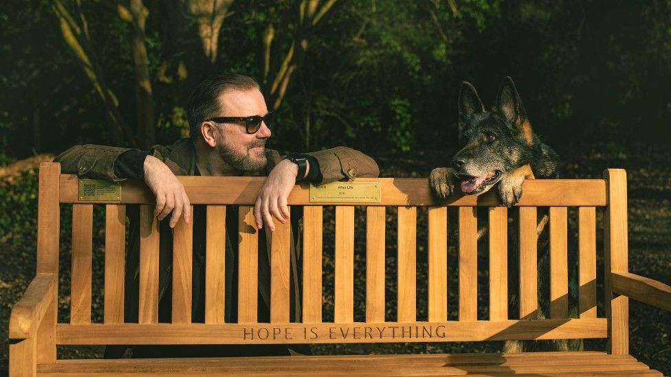 Ricky Gervais and a dog by a bench