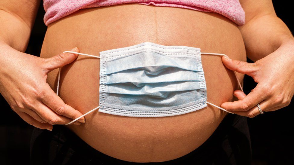 Face mask spread over a pregnant woman's stomach