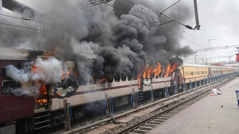 Протестующий поджег поезд Farakka Express во время акции протеста против схемы вербовки в армию Agnipath на железнодорожном вокзале Данапура 17 июня 2022 года в Патне, Индия.