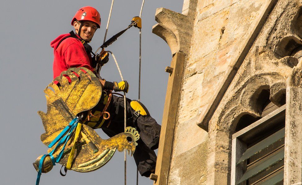Sam Milford carries the weathercock down from the spire of Norwich Cathedral