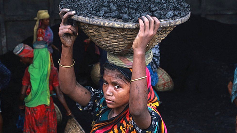 A woman carries coal as she unloads coal from a ship in Dhaka, Bangladesh on 14 September 2020