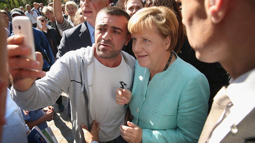 Канцлер Германии Ангела Меркель делает паузу, чтобы сделать селфи с мигрантом