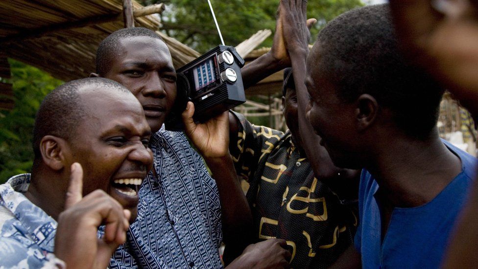 kenyan men listen to radio