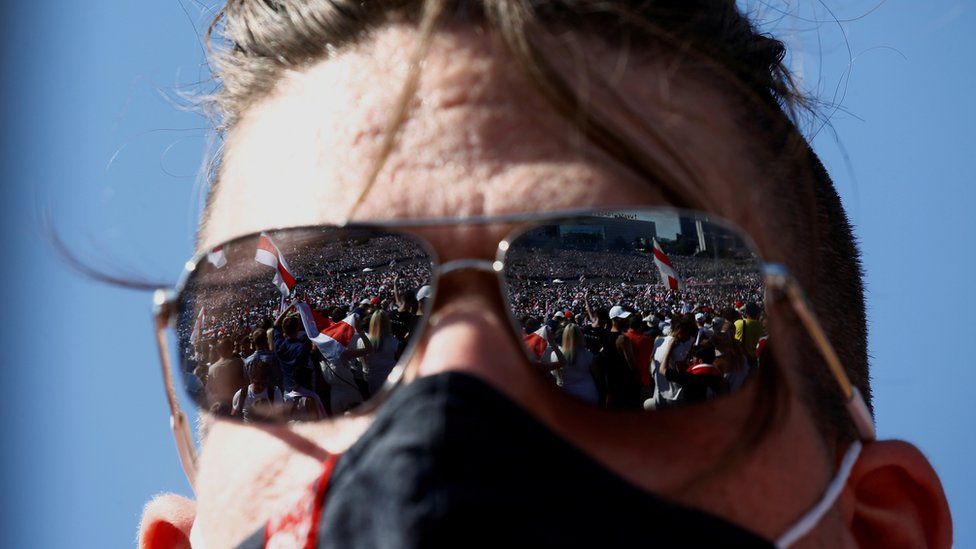 Demonstrators are reflected in the sunglasses of a participant during a protest against the presidential election results
