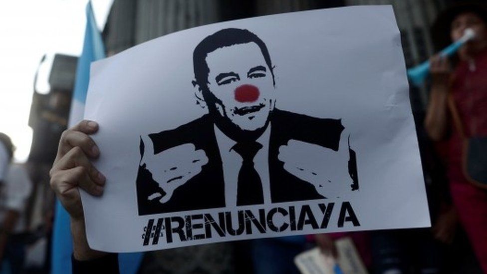 A protester holds up a sign calling for the resignation of Guatemalan President Jimmy Morales