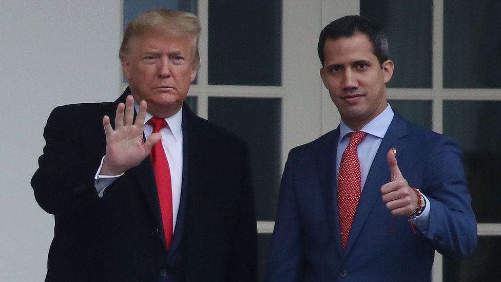 Guaidó gives a thumbs up to the camera while Trump holds his hand out in front of him