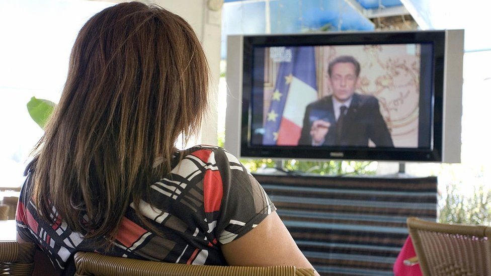 A woman in Guadeloupe watches former French President Nicolas Sarkozy on TV in 2009