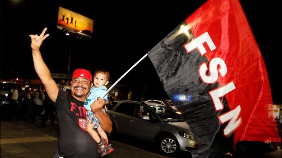 A supporter of Nicaragua's President Daniel Ortega and vice presidential candidate, his wife, Rosario Murillo, holds up a flag of the Sandinista National Liberation Front, or FSLN, while celebrating after preliminary results showed Ortega was on course for re-election, in Managua, Nicaragua November 6, 2016.