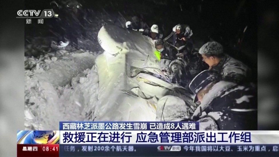 Rescuers try to pull a vehicle trapped in the snow after the avalanche in Tibet