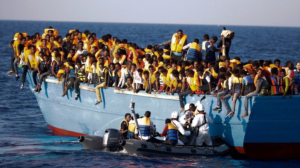 Italian officers rescue a woman from a crowded wooden boat