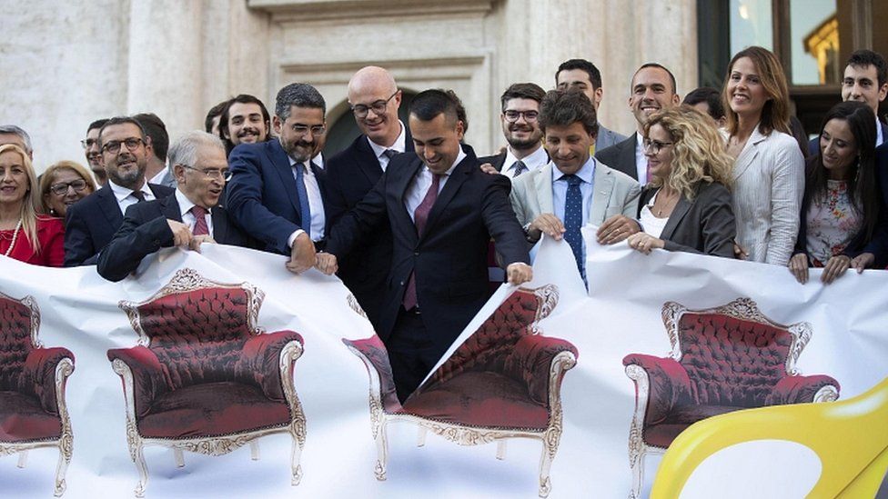 Italian Foreign Minister Luigi Di Maio (C), rips a banner with photos of MPs' armchairs exhibited by the M5S parliamentarians in front of the Chamber of Deputies in Rome, 8 October 2019