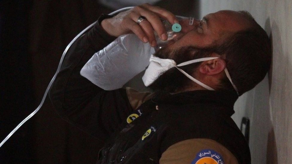 A civil defence member breathes through an oxygen mask, after what rescue workers described as a suspected gas attack in the town of Khan Sheikhoun