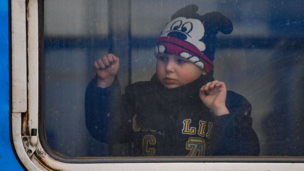 A child looks out of a train window at a station in Poland as refugees are relocated across the country