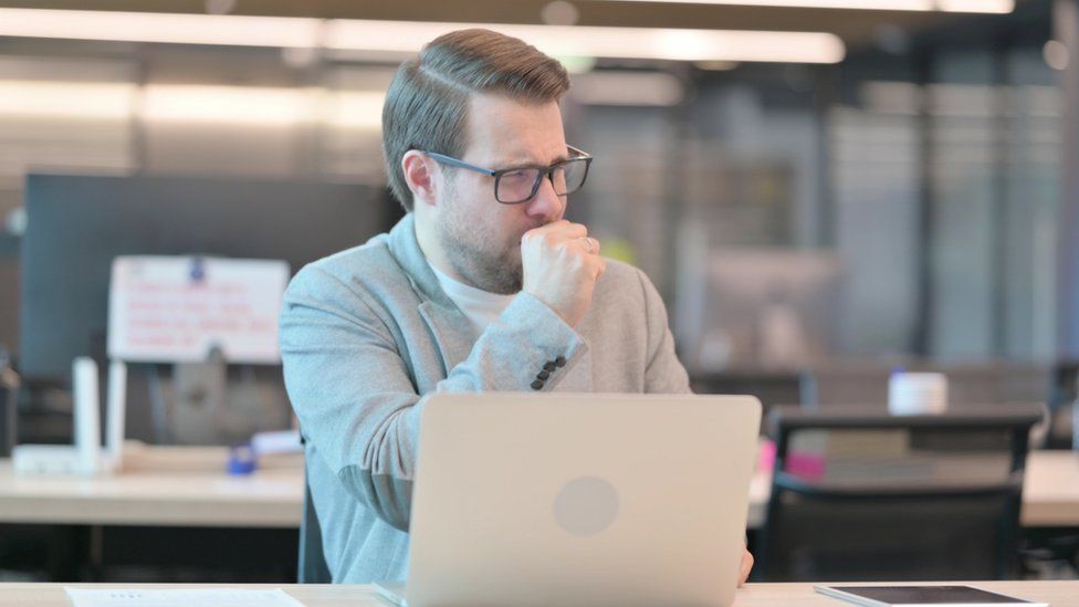 A man coughing at work