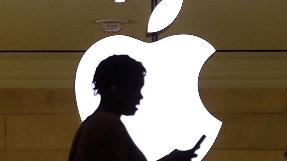 фотография человека, проверяющего свой телефон перед логотипом Apple