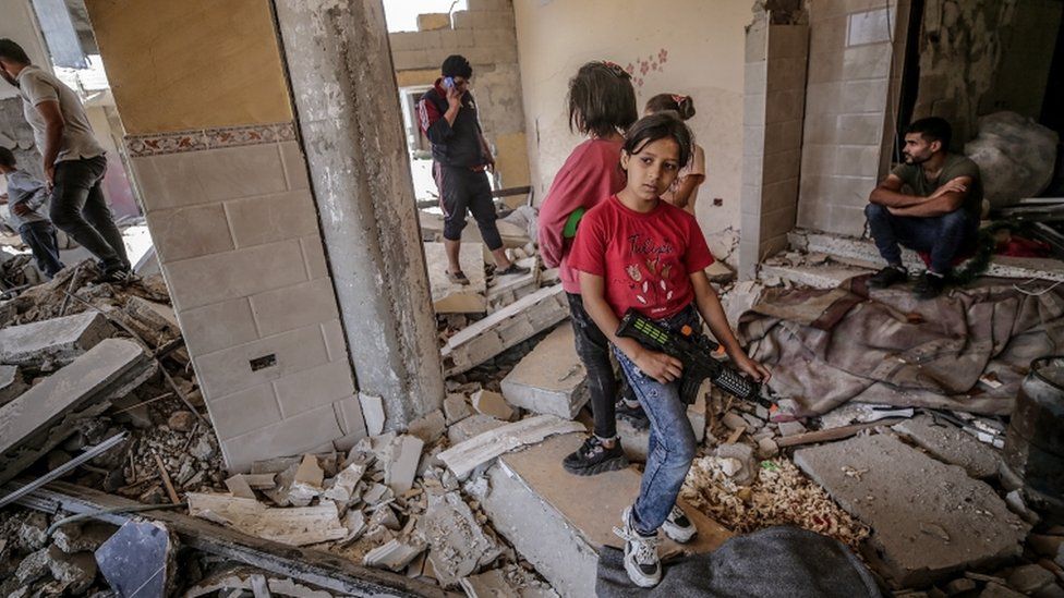 Palestinian girls stand at the rubble of their destroyed house in Gaza