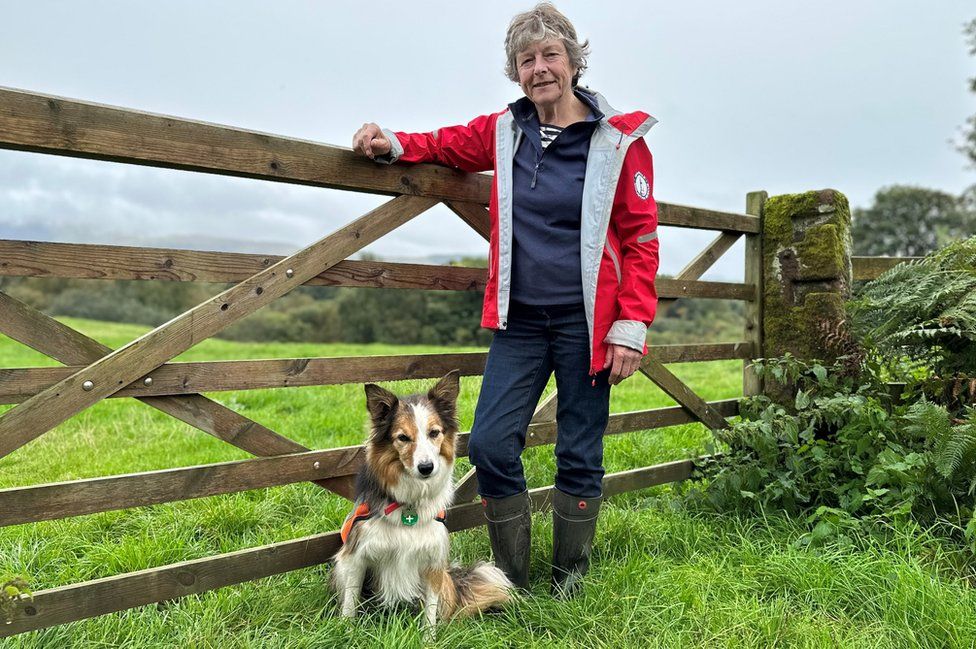 A woman and dog stand next to a gate