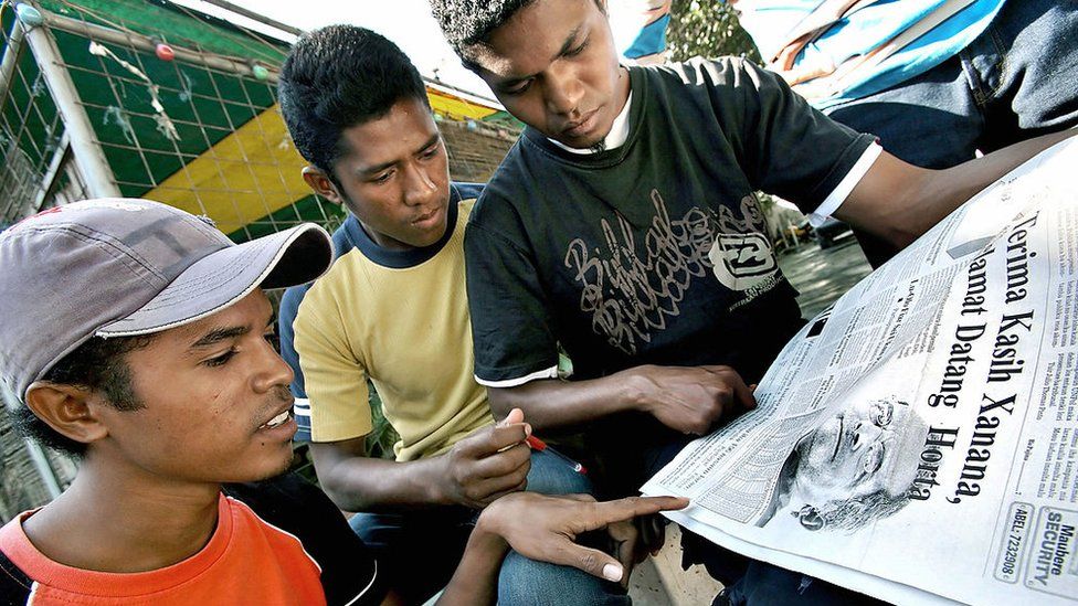 Tres jóvenes de Timor Oriental leen un periódico