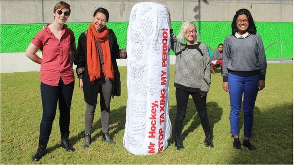 Subeta Vimalarajah and fellow campaigners hold up tampon-shaped protest sign