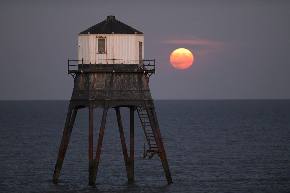 The full Sturgeon supermoon rises behind the Dovercourt Lower Lighthouse in Essex