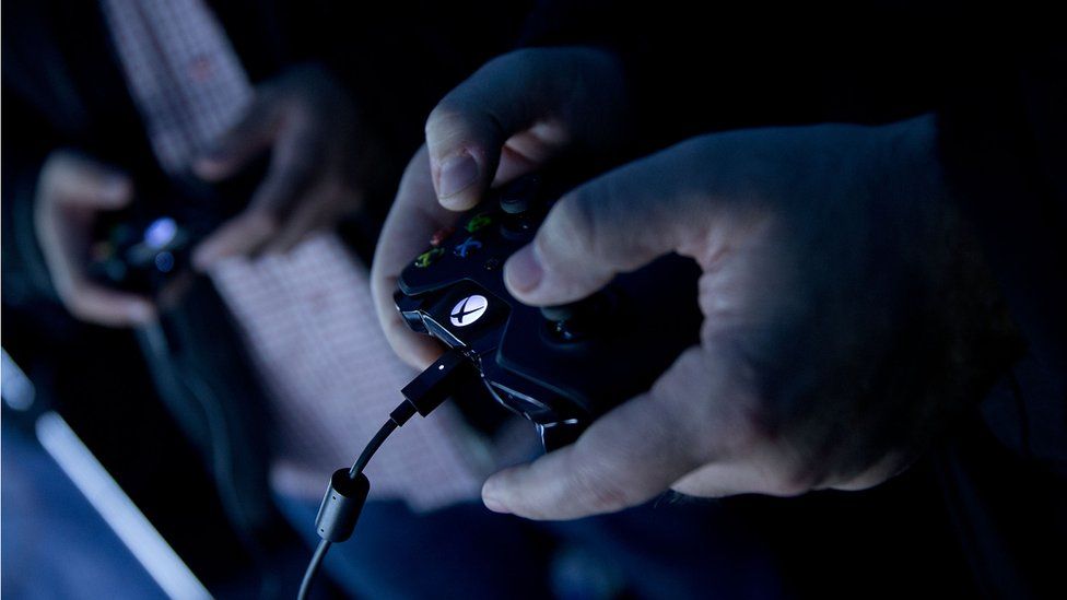 Two gamers play Xbox in a dark room