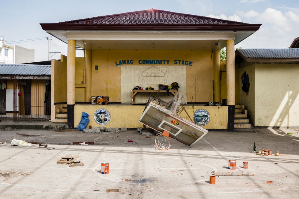 A basketball hoop and backboard lies broken in front of the Lamac Community Stage in the Visayan Region of the Philippines